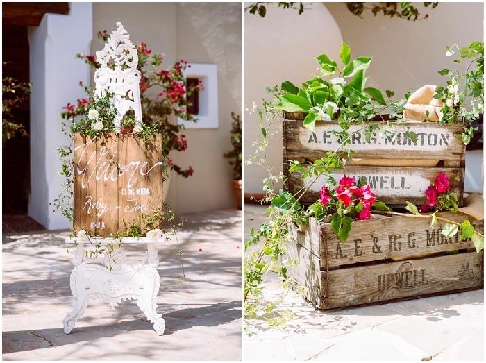 sporočilo dobrodošlice na cvetlični leseni deski na belem starinskem štafelaju, deco vinskih škatlah s cvetjem in listjem