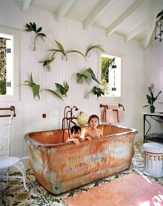iç mekan bitkisi, banyo tesisi, banyo ilgi alanı, sarkık bitki, içinde iki çocuğun banyo yaptığı eski pas efektli küvet, beyaz pvc ahşap duvarlar, çiçek desenli eski mavi ve beyaz fayans, kirişler beyaz tavan, iki pencere, aydınlık oda