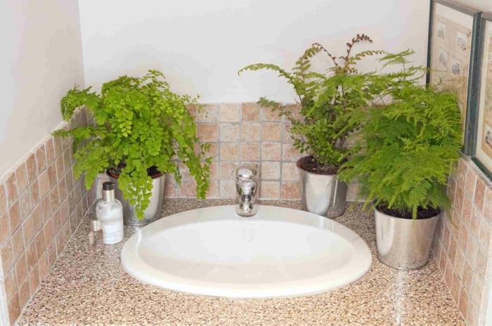 „pinterest“ vonios kambarys, drėgmę sugeriantis augalas, kambariniai augalai, balta ovalo formos kriauklė, kriauklės spintelė su marmuro spalvos viršutine dalimi rudos ir smėlio spalvos, trys sidabro spalvos metaliniai vazonai su žaliais augalais