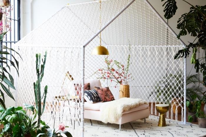 Ahşap mobilyalar ve yeşil bitkilerle altın kaplamalarla döşenmiş beyaz bir oturma odasında egzotik jungalov tarzı dekorasyon, makromede örnek oluşturma