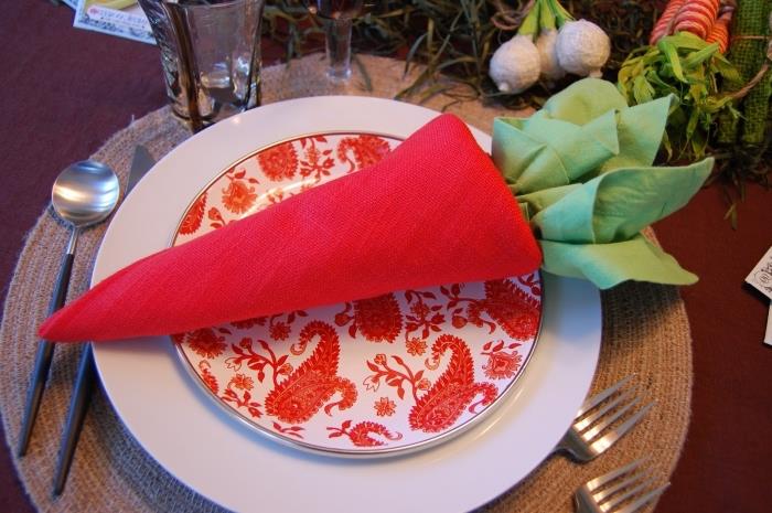 iki kırmızı ve yeşil masa örtüsünden yapılmış havuç şeklinde katlanır bir paskalya peçetesi