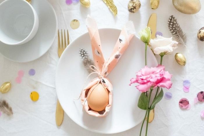 bir yumurta etrafında tavşan peçete katlama deseni, beyaz, altın ve pembe tatlı paskalya masa dekorasyonu
