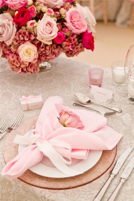 sulankstoma prašmatni vestuvių servetėlė, rožinės spalvos gėlių servetėlių laikiklis rožinėje stiklo plokštėje ir balta plokštelė, rožinių gėlių stalo centras