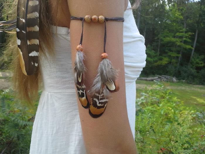 ženska tetovaža, zapestnica z lesenimi kroglicami in perjem, pričeska s perjem v laseh, tetovaža perja