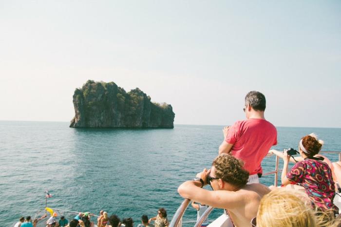 rojaus salos, rojaus kraštovaizdis, salelė vandenyno viduryje, mėlyni vandenys, turistai valtyje fotografuoja