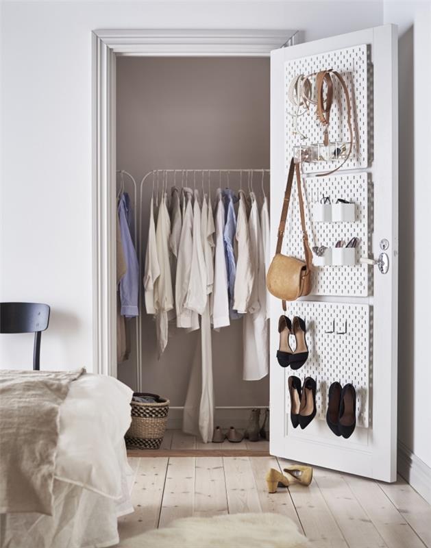 beyaz elbise askıları ve aksesuarları saklamak için kapıya asılı delikli paneller ile yatak odasında küçük giyinme odası