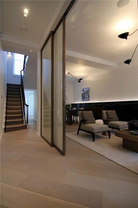 miegamojo svetainės laiptai, didelė erdvė, baltos lubos, smėlio-rudos spalvos parketas, didelis kvadratinis baltas kilimas