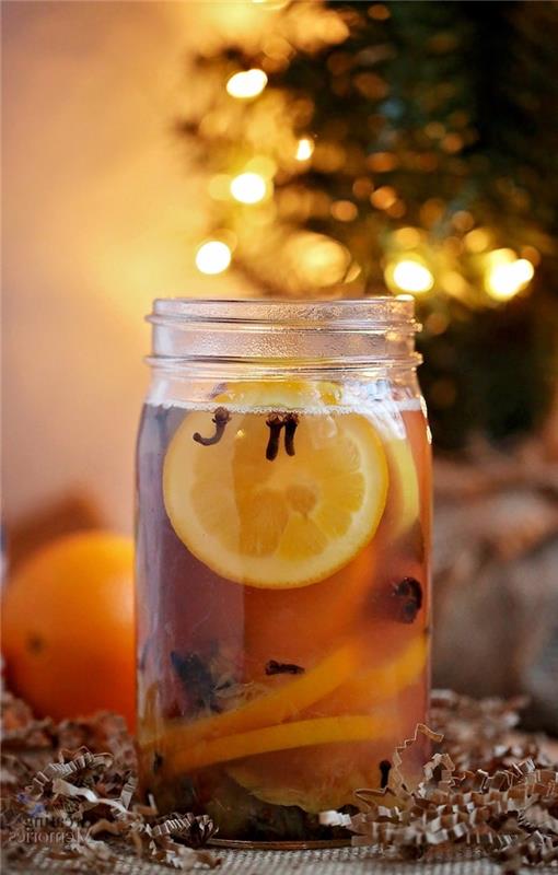 lonec pourro v steklenem kozarcu z rezinami pomaranče in limone ter različnimi božičnimi začimbami v vodi