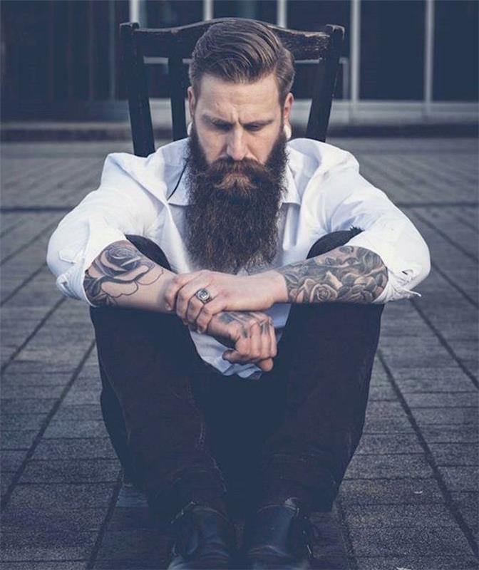 hipsterski moški videz z degradirano pričesko in tetovažo stare šole ter veliko brado