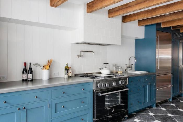 mavi bir mutfakta açıkta kalan kirişler, beyaz duvar karoları, gri tezgahlar, siyah ve gri aletler, orijinal eski mutfak