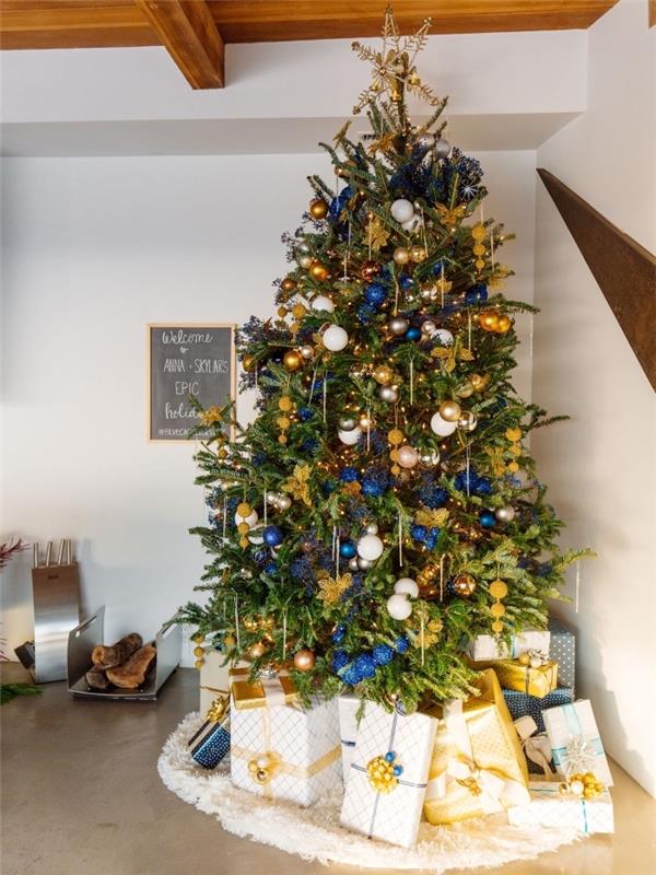 Ahşap tavanlı ve beton zeminli beyaz bir odada Noel dekorasyonu, altın ve mavi renklerde dekore edilmiş bir Noel ağacı örneği