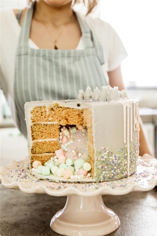 presenetljiva torta iz vanilijeve biskvitne torte s tekočo glazuro, napolnjeno z mešanico užitnega prahu, sladkornih biserov in marshmallowa