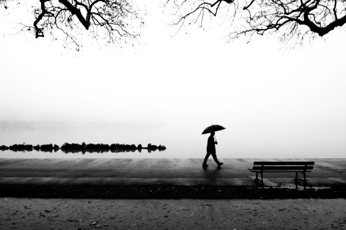 črno -bela fotografija sprehajališče ob obali, enobarvna fotografija moškega, ki drži dežnik