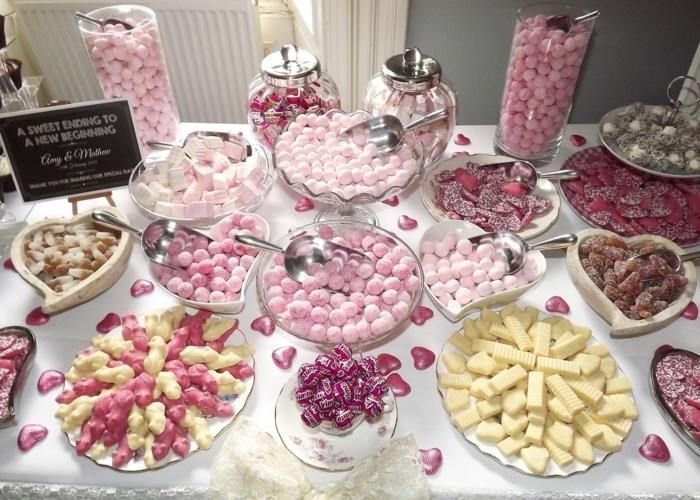 poročna sladkarija, sladkani mandlji, marshmallows, gumbi, karamele, sladki koren, beli prt, posut s čokoladnimi bonboni v obliki srca, steklene škatle za sladkarije v obliki srca, beli trak