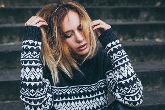 ženski model puloverja v črni barvi z geometrijskimi vzorci v beli barvi, blond ombre z bakrenimi poudarki na rjavih laseh