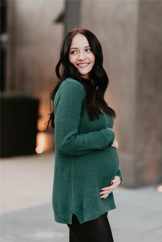 Nėščiųjų kelnių idėja juodos spalvos, nėščia moteris atrodo žalios spalvos megztiniu ir juodais antblauzdžiais, motinystės mada