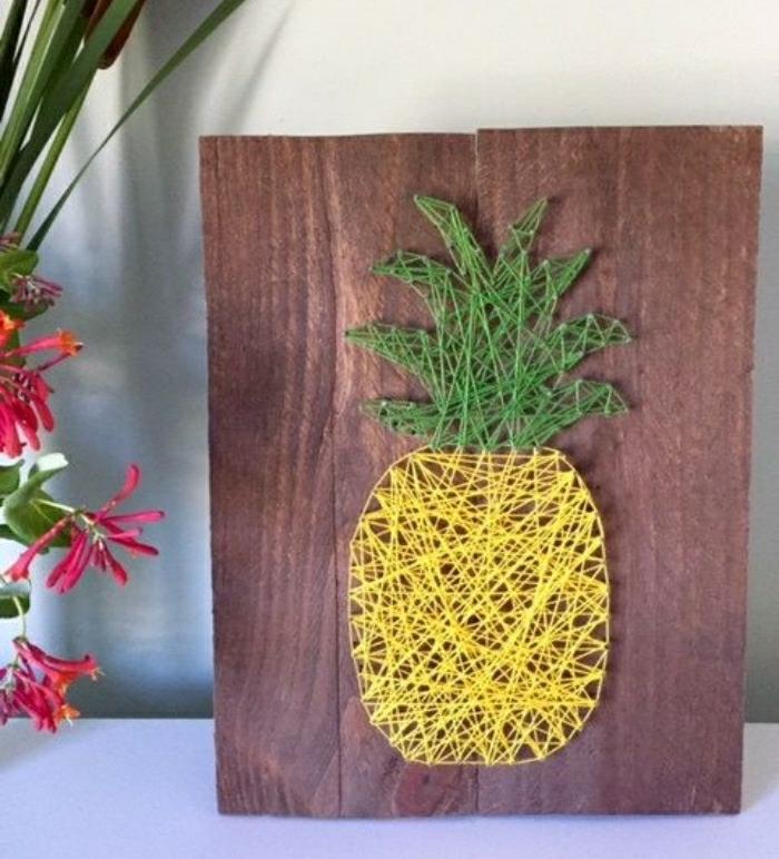 Lavori artigianali fai da te per decorare la casa, pezzo di legno con un ananas di corda gialla e verde