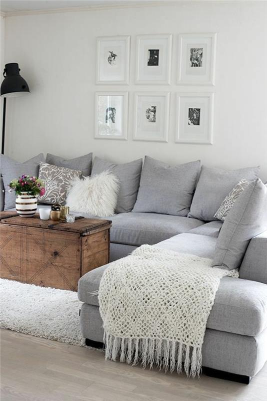 inci grisi oturma odası, büyük gri minderli köşeli açık gri kanepe ve beyaz çerçeveli altı masa