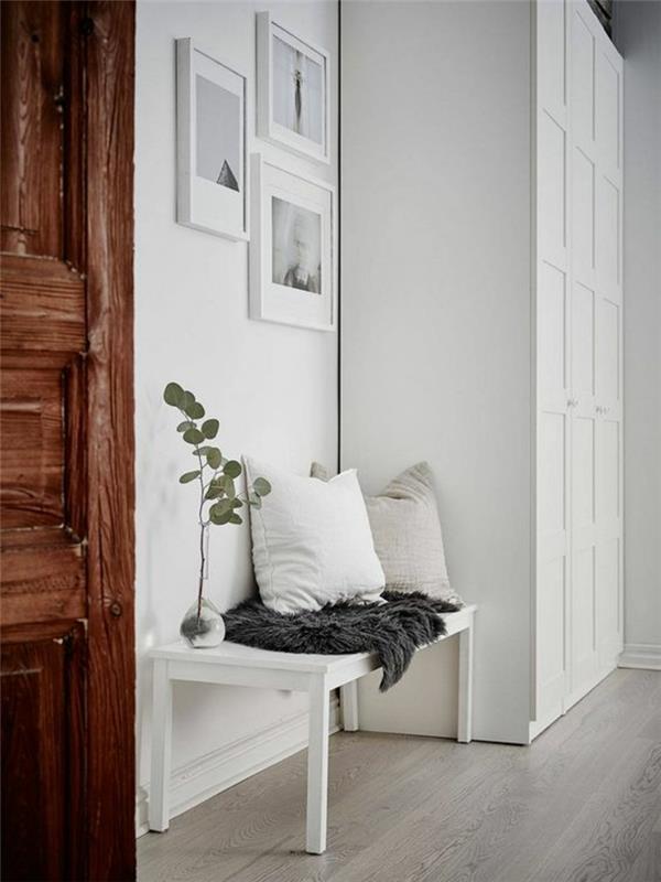 kaip papuošti prieškambarį balta ir pilka spalva, trys nuotraukos baltu rėmu ant baltos sienos, didelė balta spintelė su dekoratyviniais plytelių raštais, tamsiai rudos medinės durys