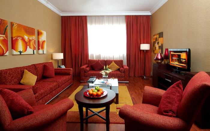 renk kombinasyonu, kırmızı ve koyu bej, kırmızı kanepe ve koltuklar, sarı ve turuncu halı, kahverengi TV dolabı