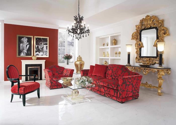 barvna kombinacija rdeče rjave stene, kavč, naslanjač in rdeč stol, steklena mizica, bela lakirana tla, ogledalo z zlatim okvirjem in okrasni zlati naglas