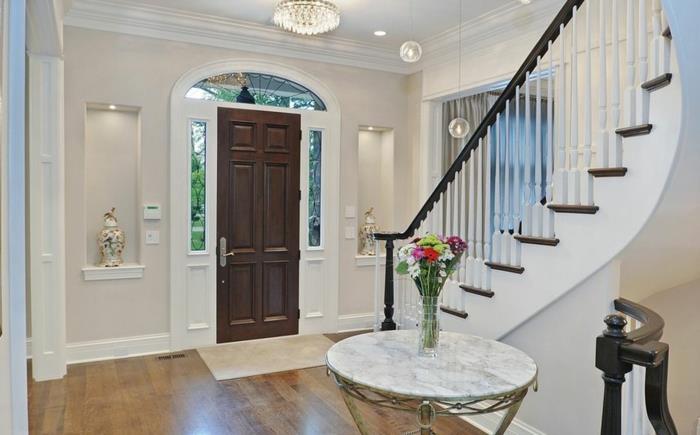 sodobna luksuzna hiša, dekoracija vhoda v dom, okrogla marmorna miza, vhodna vrata iz temnega lesa, stopnišče
