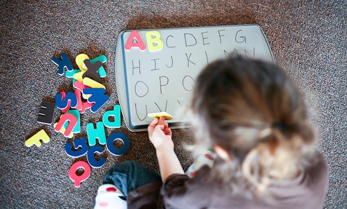 Üzerinde harfler yazılı manyetik tahta ve ilişkilendirmek için manyetik harf şekilleri, alfabeyi ve renkleri öğrenme, çocuklar için montessori etkinlikleri