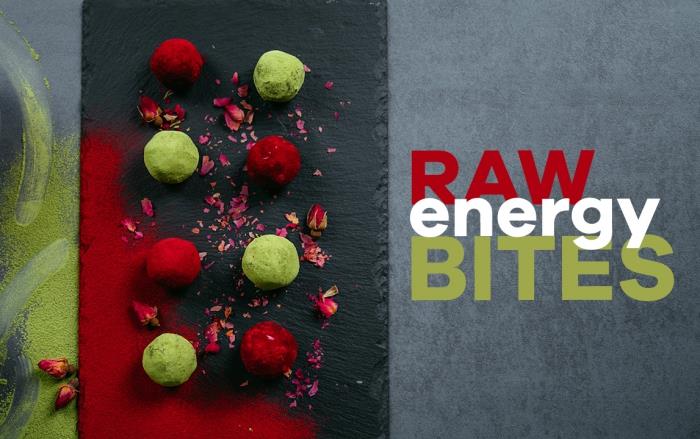 žalios energijos kąsneliai, juoda pjaustymo lenta, žemės riešutų sviesto baltymų rutuliukai, padengti kakava, nudažyti žalia ir raudona spalvomis