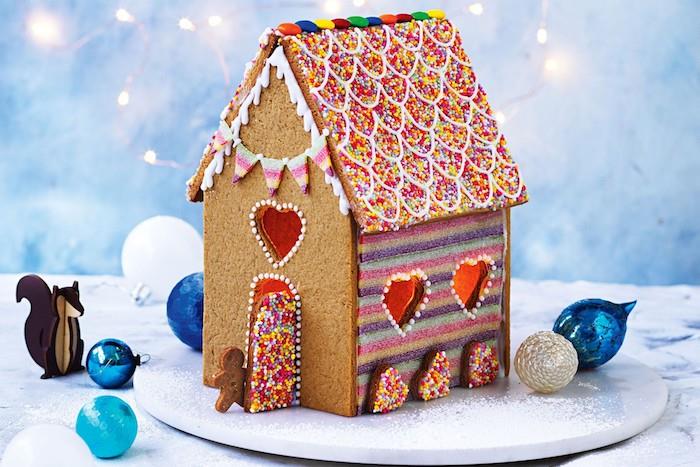 renkli sprinkles, renkli çizgili duvar ve sprinkle tutucu ile dekore edilmiş çatılı gurme Noel zencefil evi