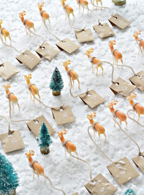 Advento kalendorius mažose elnių figūrėlėse, Kalėdų elniai su mažais kabančiais kraftiniais maišeliais, Kalėdų eglutės figūrėlės ant dirbtinio sniego