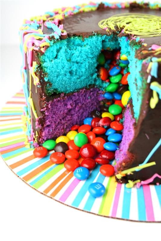 ideja za domačo rojstnodnevno torto, torto smarties, prekrito z ganachejem, sestavljeno iz dveh slojev modre in vijolične biskvitne torte, ki vsebuje bonbone