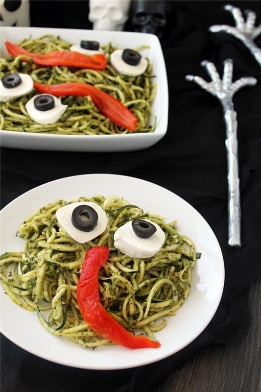 Pošasti za noč čarovnic v testeninah iz zelenega pesto, s koščki mozzarelle in rezinami oljk, ki tvorijo oči