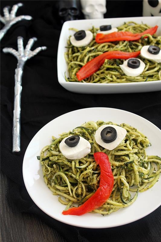 Pošasti za noč čarovnic v testeninah iz zelenega pesto, s koščki mozzarelle in rezinami oljk, ki tvorijo oči