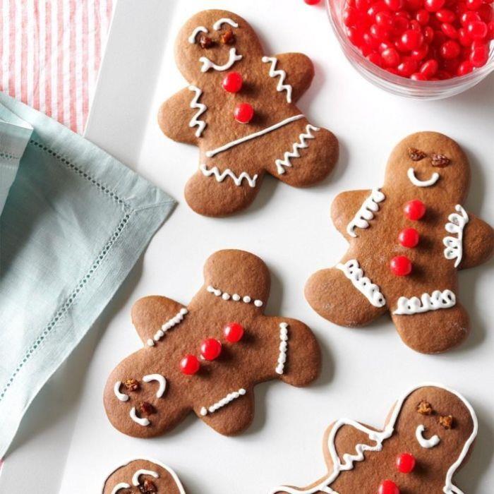 Ideja za recept za božični pecivo medenjaki piškotek, okrašen s svežo smetano in rdečimi sladkornimi mandlji v belem krožniku