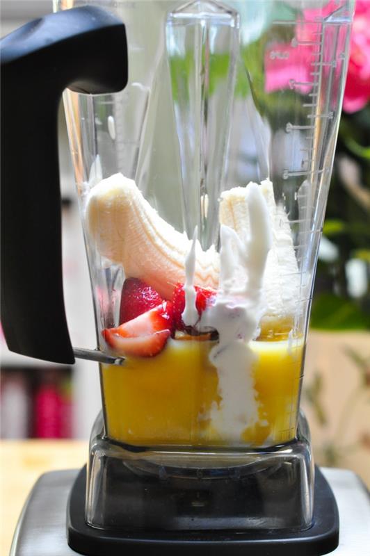 priprava bananinega smoothieja z limoninim sokom in jagodami v mešalniku