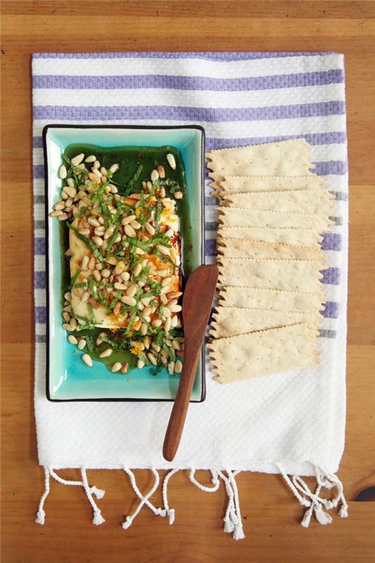 vegetarijanski aperitiv, izvirna ideja za aperitiv na osnovi sira, recept za sir feta, pokapan z medom in okrašen s pinjolami na žaru, pomarančno lupino in meto