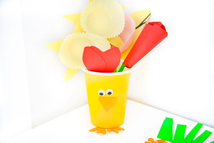 plastikinis viščiuko puodelis sukiojančiomis akimis ir popierinis snapelis, užpildytas spalvingomis popierinėmis gėlėmis su paprastu popieriumi ir bandelių puodeliais