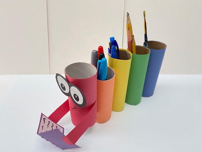 Bir kitap kalemlik masası tutan renkli şönil desenli kağıtla süslenmiş tuvalet kağıdı rulolarını geri dönüştürmek