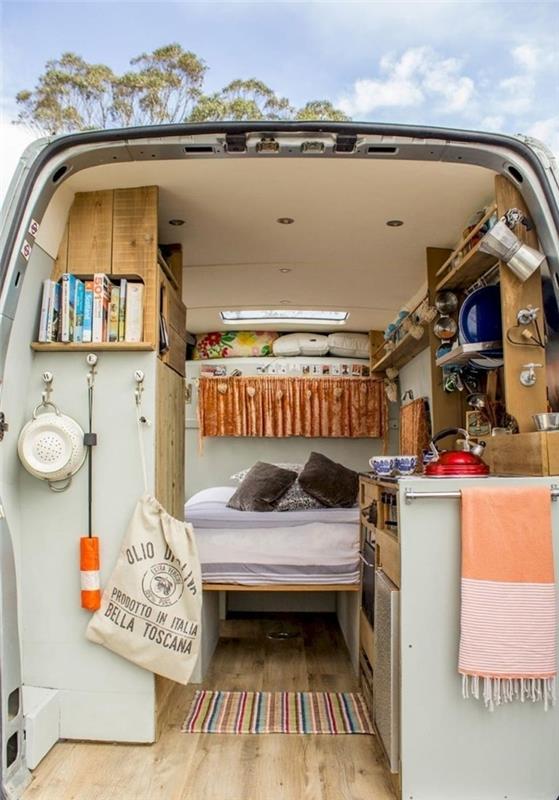 Renault trafic vgrajena postelja in majhno kuhinjsko leseno pohištvo stensko skladišče lesena polica večbarvna preproga temno siva blazina