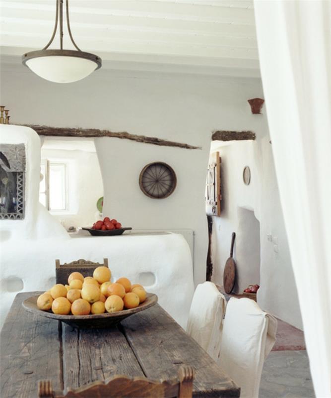 Grška dekoracija, bele stene, okras iz kamna in lesa, limone, stara lesena miza