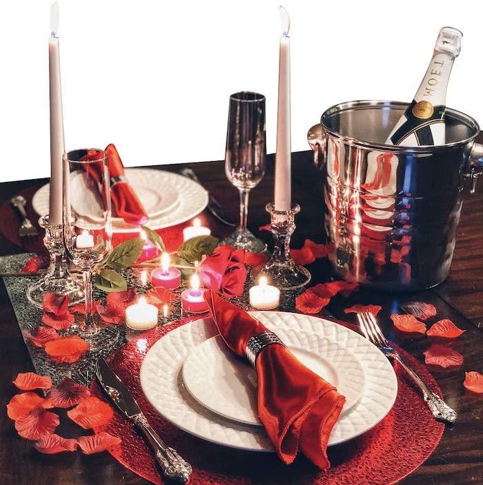 romantiškas maistas idėja padengti stalą su rožių žiedlapiais ir raudonomis servetėlėmis į dvi lėkštes