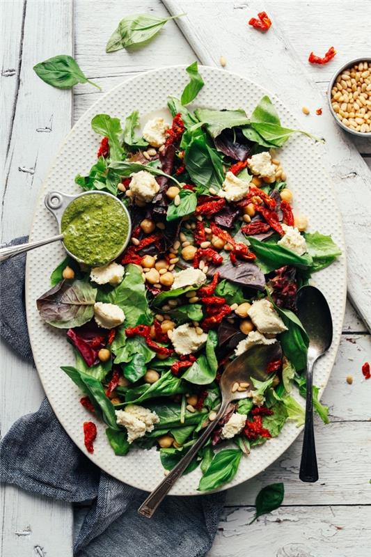 žalių salotų receptas, pagamintas iš špinatų, saulėje džiovintų pomidorų, avinžirnių, patiekiamų su daržovių rikota su migdolais ir pesto padažu