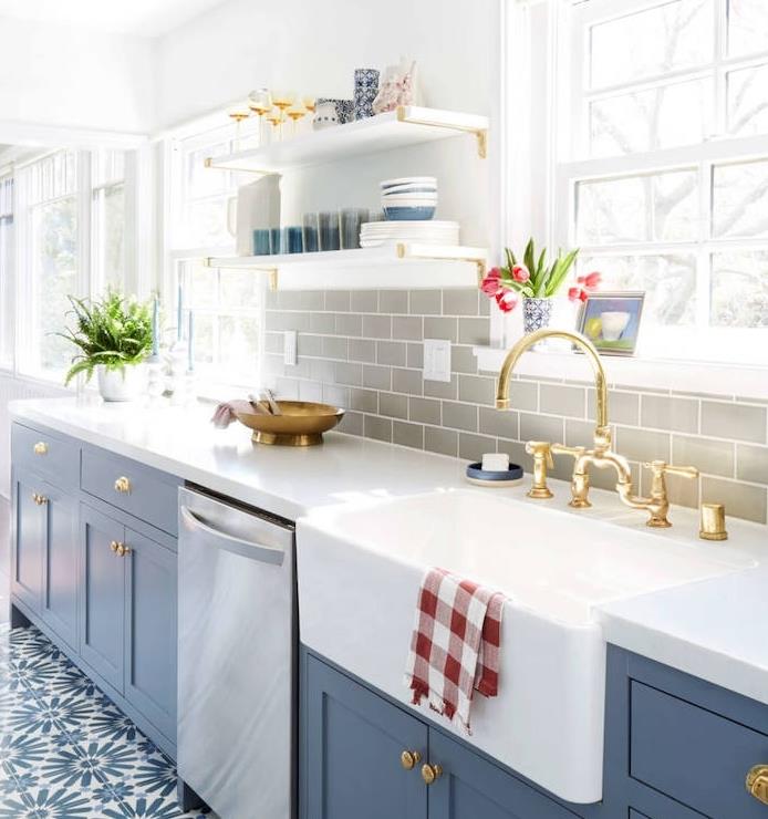 pertvarkyti virtuvę, plytelėmis išklotos plytelės perdažytos pilkai tamsiai mėlynos spalvos virtuvės fasadu, baltu stalviršiu ir baltomis bei mėlynomis grindų plytelėmis su gėlių raštais