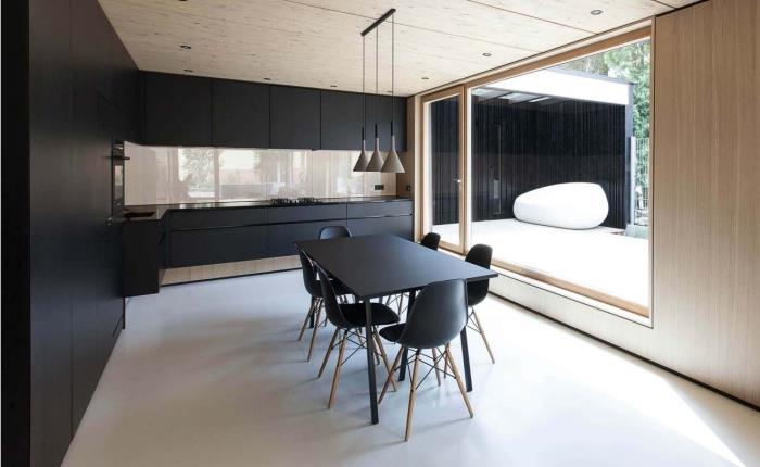 minimalistinis virtuvės išdėstymas su juodomis spintelėmis ir šviesaus medžio lubomis, pramoninio stiliaus grindų lempa juodos ir taupe spalvos, virtuvės modeliai