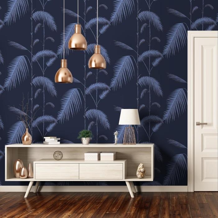atogrąžų džiunglių tapetų raštas tamsiai mėlynos ir pilkos spalvos, modernus interjero dekoras su šviesaus medžio baldais ir vario aksesuarais