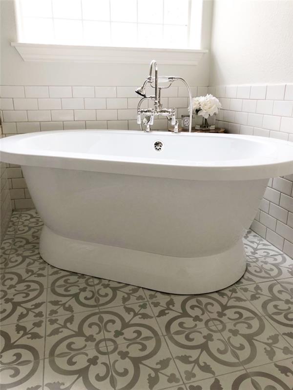 cemento vonios plytelės su arabesko raštais ir baltos metro plytelės eina koja kojon šiame monochrominiame vonios kambaryje