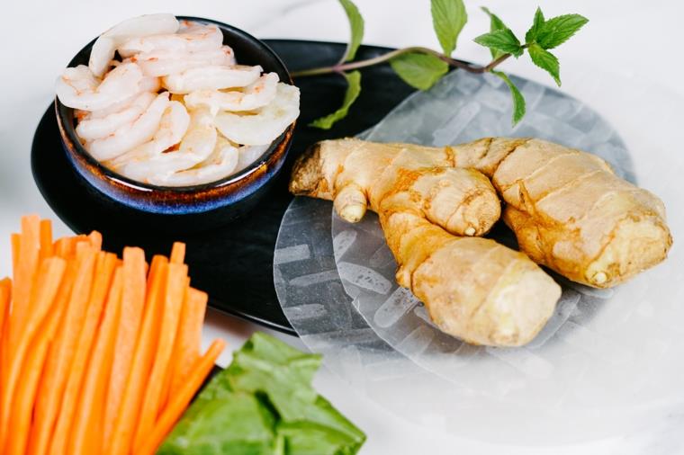 Piatto con carta di riso e zenzero, ciotola con gamberi saltati in padella