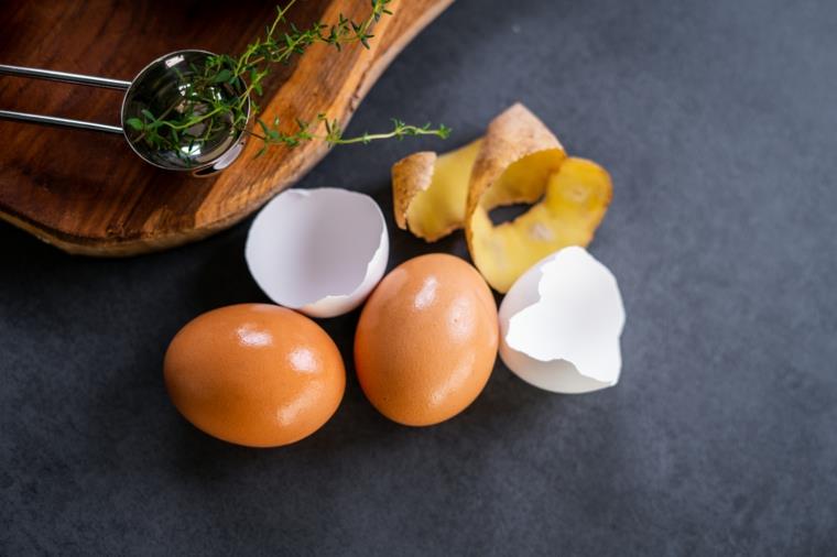Buccia di patate e due uova, ricette con uova e potate, tagliere di legno con erbette
