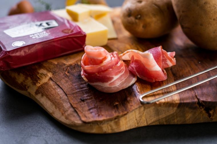 Ricette con uova e krompir, fette di slanina, tagliere di legno s sestavinami sopra