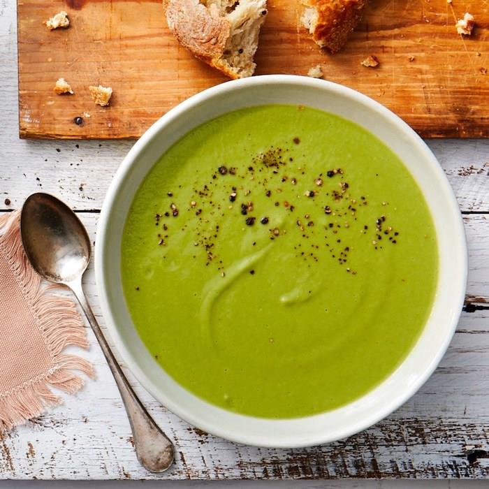 Zuppe dietetiche, piatto con vellutata verde, tagliere di legno con pezzi di pane